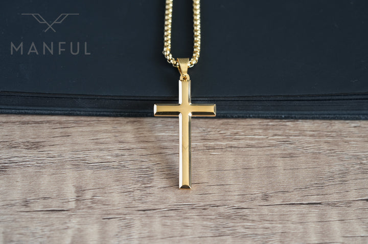 Cross Pendant Necklace Gold, laid on a wood surface against a black book edge