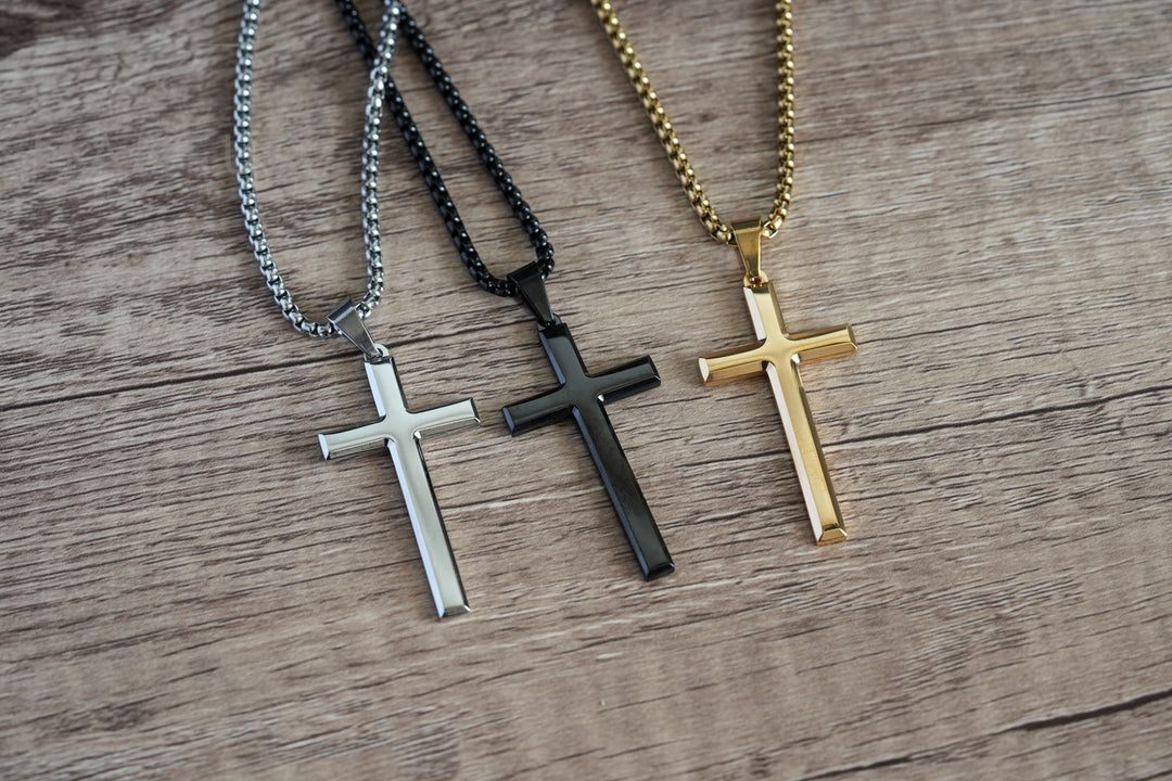 Cross Pendant Necklace Gold, laid on wood beside the matching silver and black colour variants
