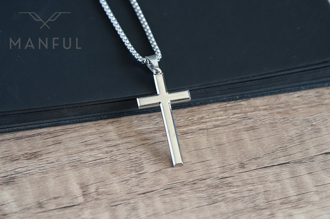 Cross Pendant Necklace Silver, laid flat on a dark surface with the chain coiled beside it