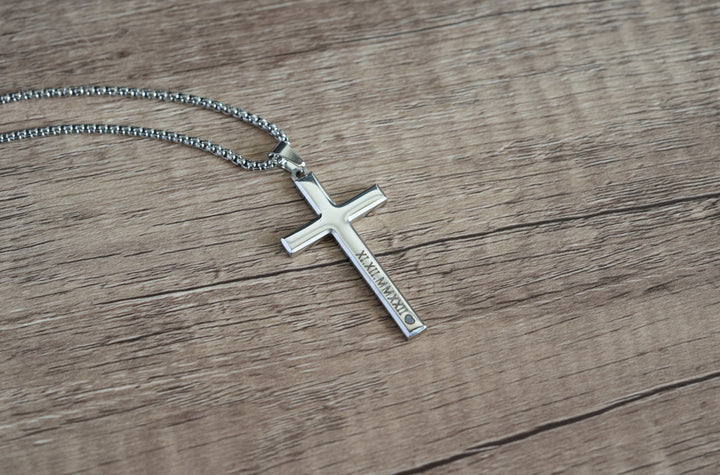 Cross Pendant Necklace Silver, close-up on a wood surface showing engraved text on the cross