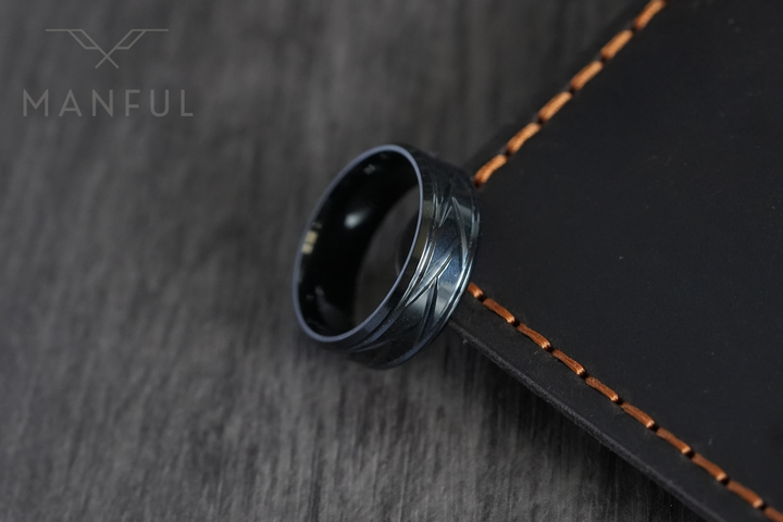 Crosscut Band Black, propped against a leather-edged notebook with orange stitching