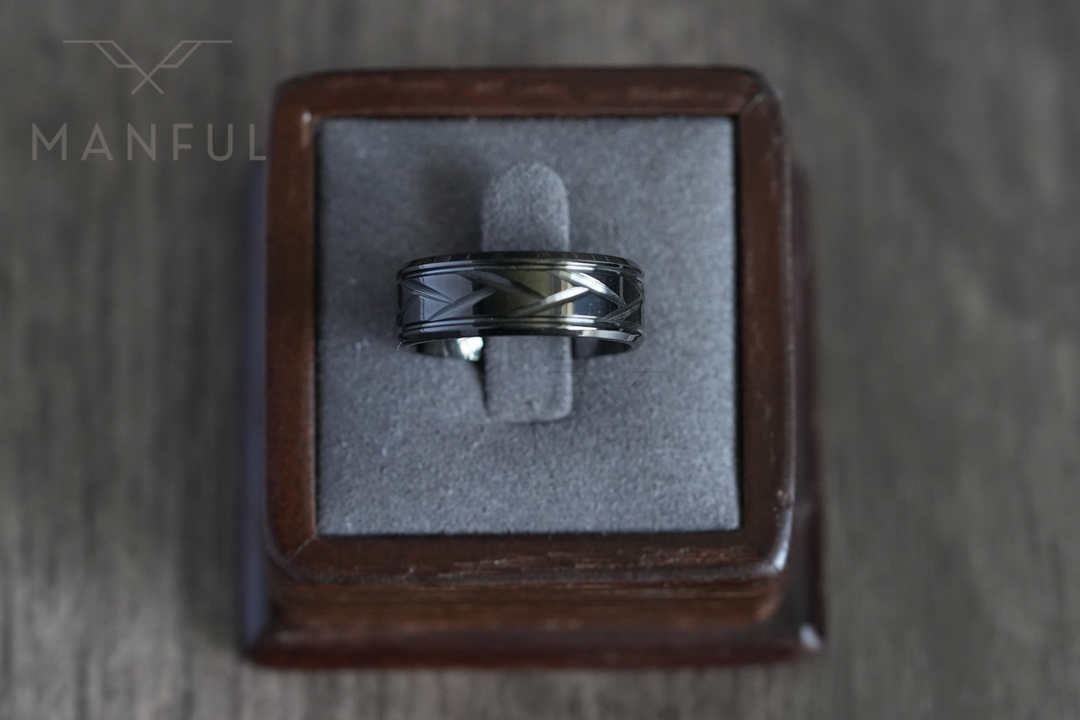 Crosscut Band Black, standing in a wooden ring box on a grey velvet cushion