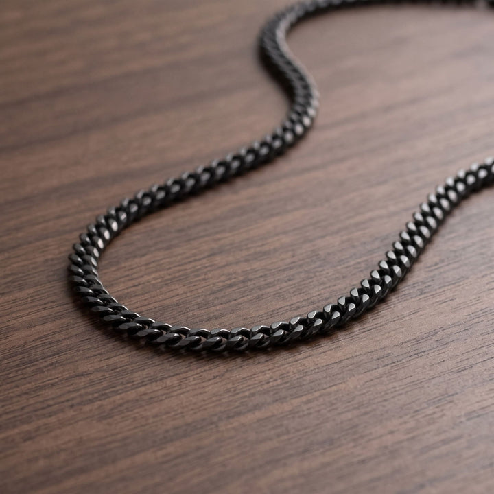 Cuban Chain 3mm Black lying in a loose curve on a walnut table
