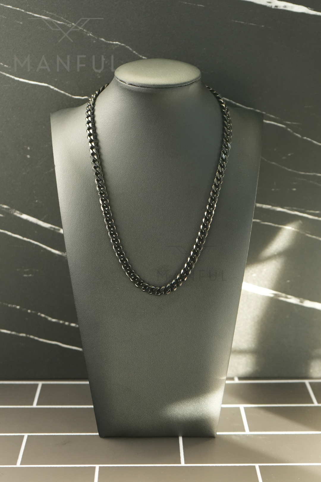 Cuban Chain 7mm Black, displayed on a dark bust with a marble tile background