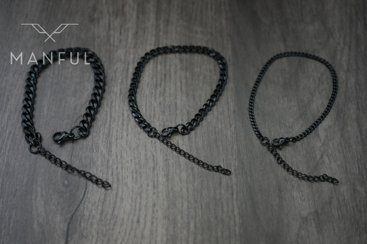 Cuban Chain Bracelet Black, three widths laid side by side on a wood surface