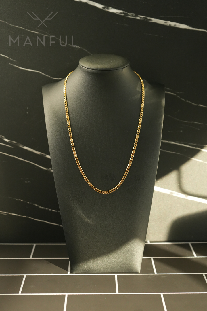 Cuban Chain 3mm Gold, displayed on a black necklace bust against a dark tiled background
