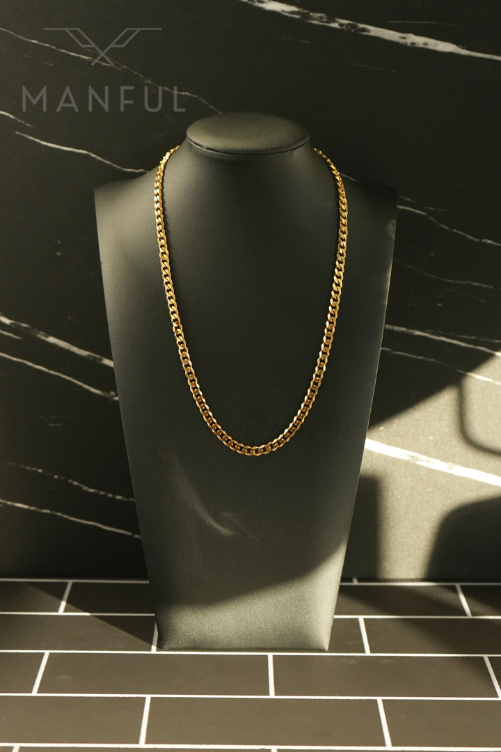 Cuban Chain 5mm Gold, displayed on a black bust against a dark marble backdrop