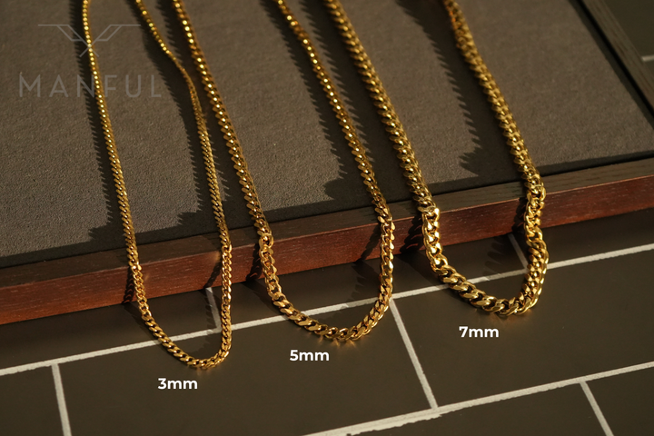 Cuban Chain 7mm Gold, draped over a wooden box edge next to two thinner width options