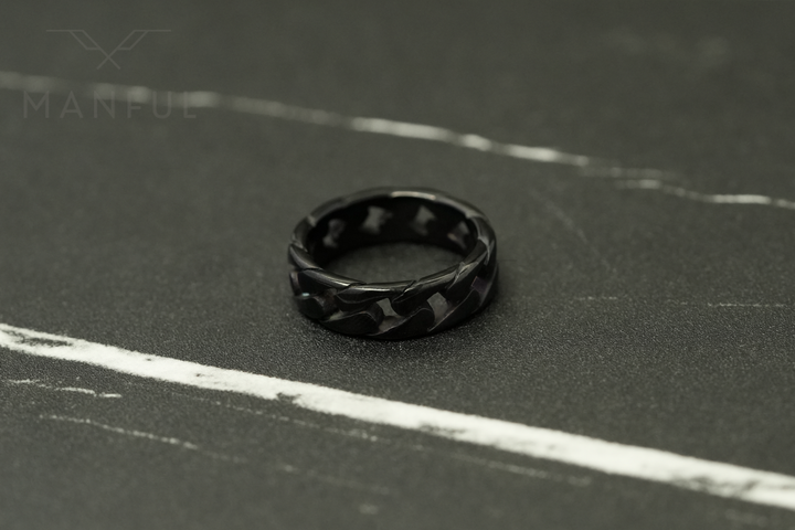 Cuban Chain Ring Black, standing upright on a dark marble surface