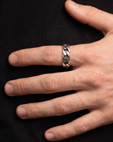 Cuban Chain Ring in silver worn on the index finger of a freckled hand resting flat on a black tee