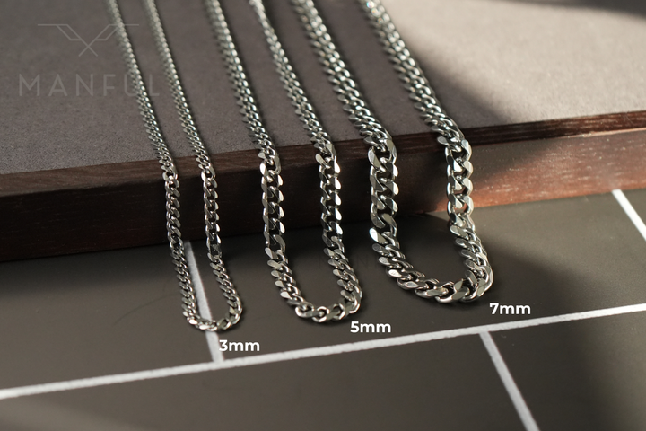 Cuban Chain 5mm Silver, shown in three widths draped over a wood edge, labelled 3mm to 7mm