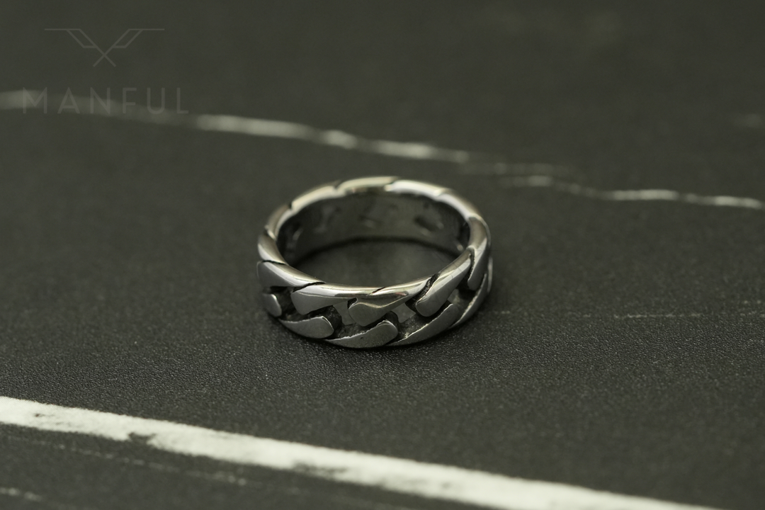Cuban Chain Ring Silver, standing on a dark marble surface with white veining