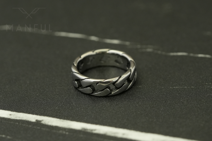 Cuban Chain Ring Silver, standing on a dark marble surface with white veining