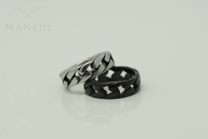 Cuban Chain Ring Silver, propped in front of its black colourway on a light background