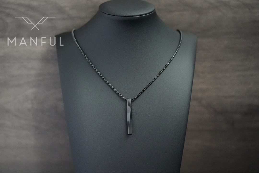 Cuboid Pendant Chain Black, worn on a display bust against a wood-panelled background