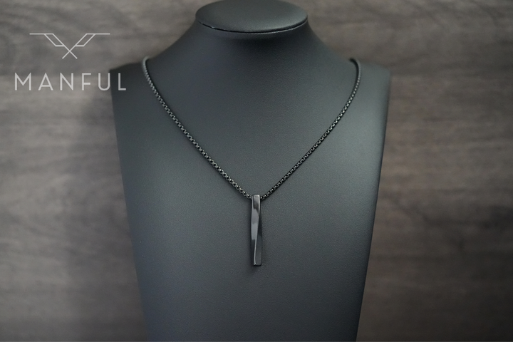 Cuboid Pendant Chain Black, worn on a display bust against a wood-panelled background