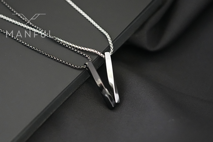Cuboid Pendant Chain Black, paired with the silver colourway pendant on dark fabric