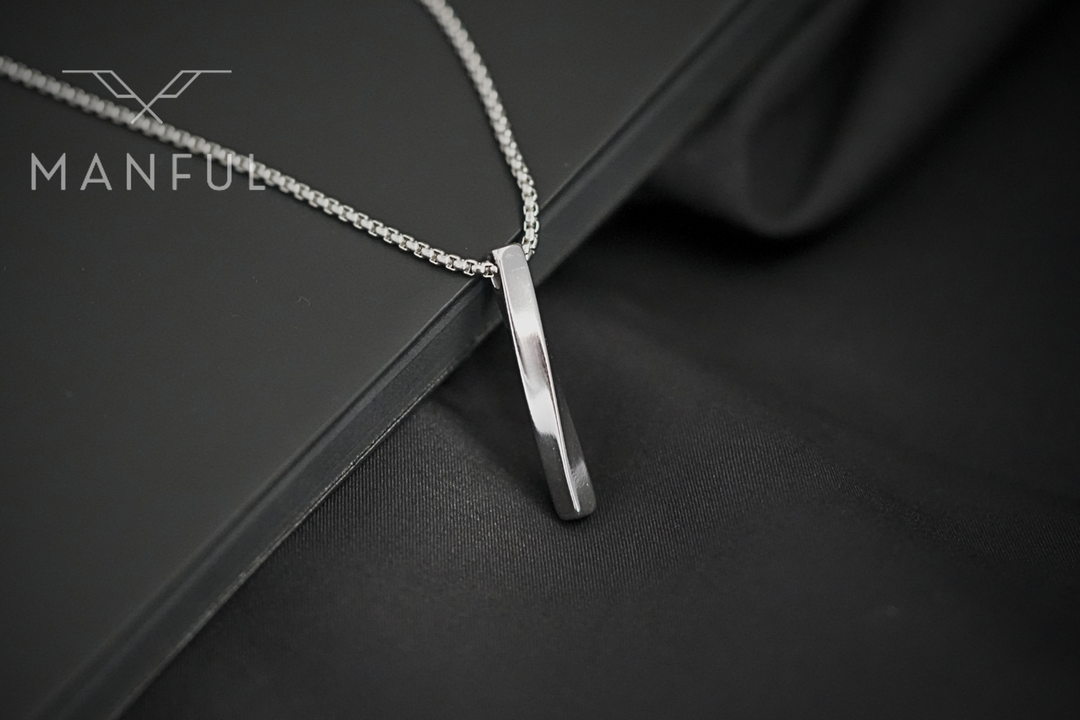 Cuboid Pendant Chain Silver, close up on the bar pendant draped over dark leather