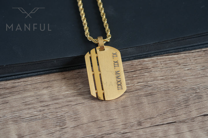 Dog Tag Chain Gold, close-up on a black book showing a custom roman numeral date engraving