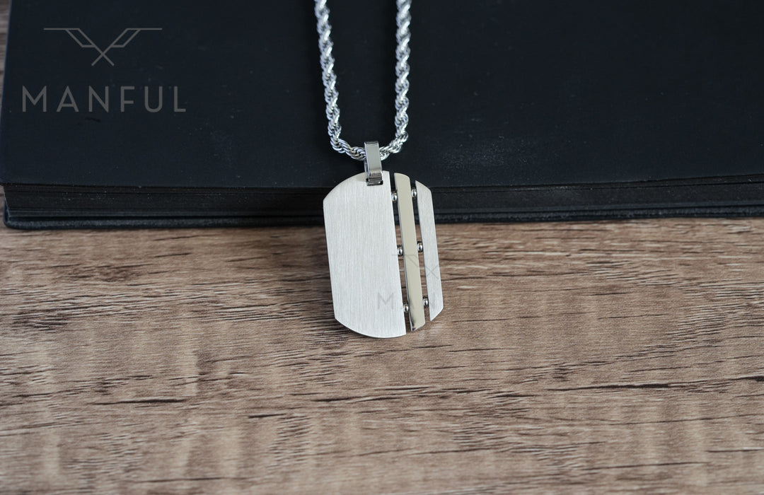 Dog Tag Chain Silver, leaning upright against a black book on wood
