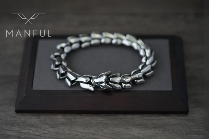 Dragon Link Bracelet Silver, resting on a grey display pad framed in dark wood