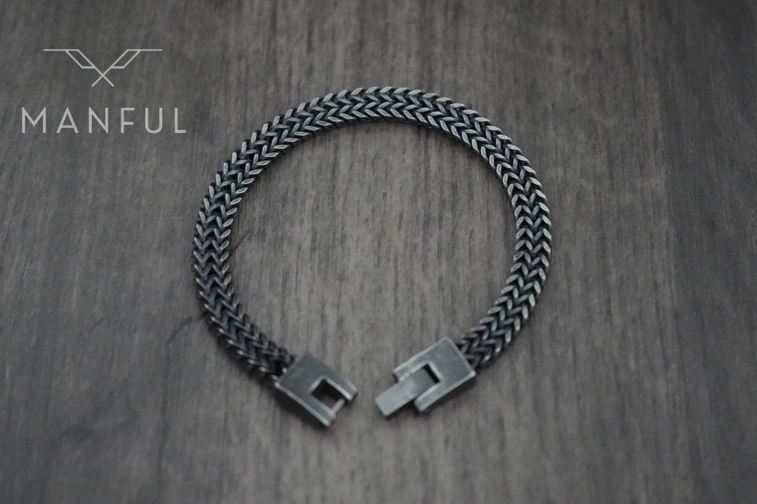 Foxtail Bracelet Dark Grey, laid flat on wood with the box clasp open