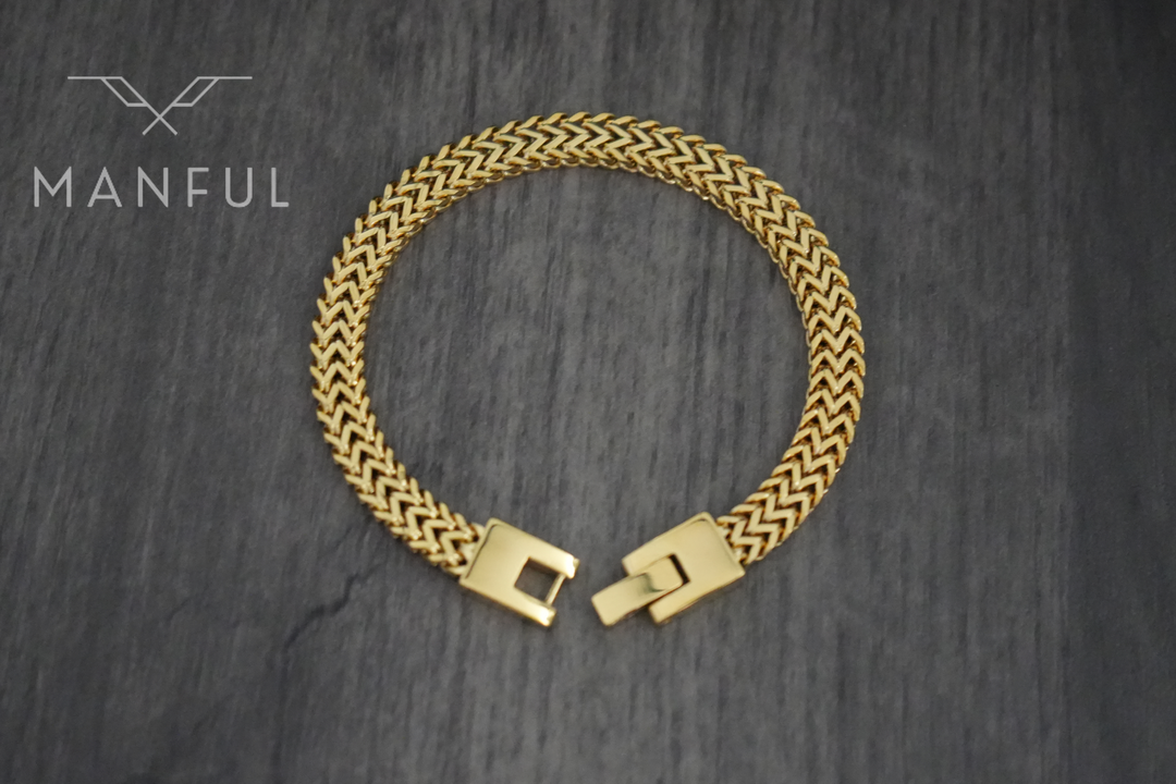 Foxtail Bracelet Gold, laid in a circle on a dark wood surface showing the clasp from above