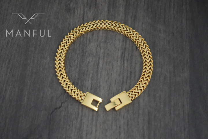 Foxtail Bracelet Gold, laid in a circle on a dark wood surface showing the clasp from above