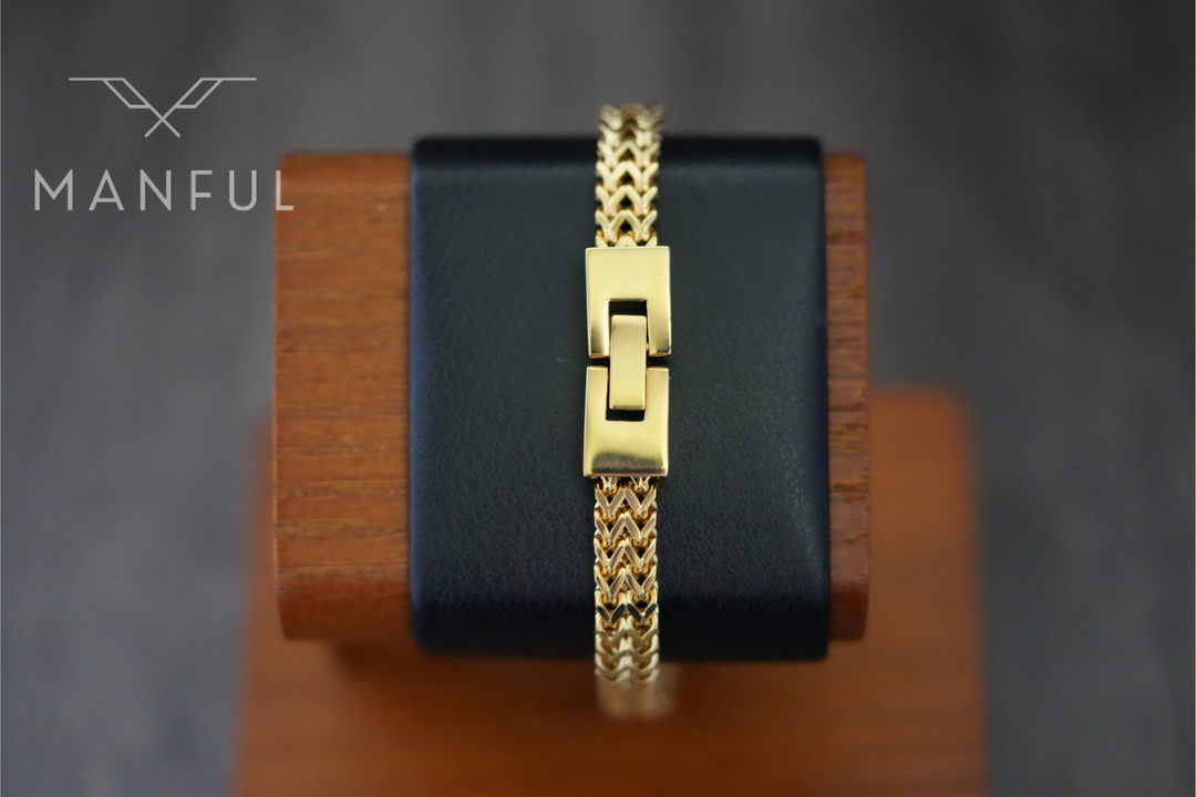 Foxtail Bracelet Gold, draped over a black leather stand showing the box clasp closed