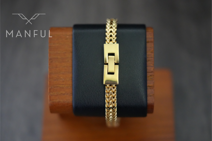 Foxtail Bracelet Gold, draped over a black leather stand showing the box clasp closed