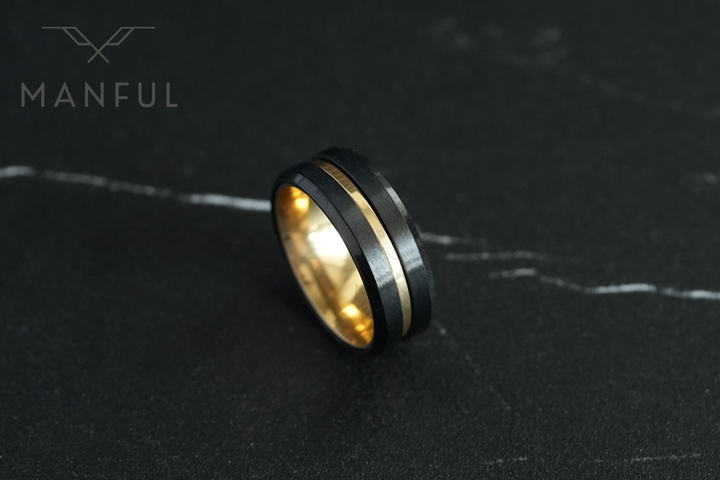 Gold & Black Band, angled on a dark marble surface showing the gold centre groove