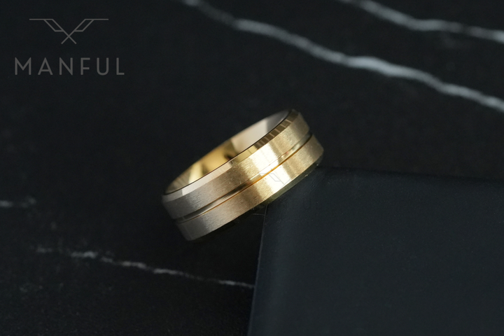 Gold Band, leaning against the edge of a black box on a marble surface