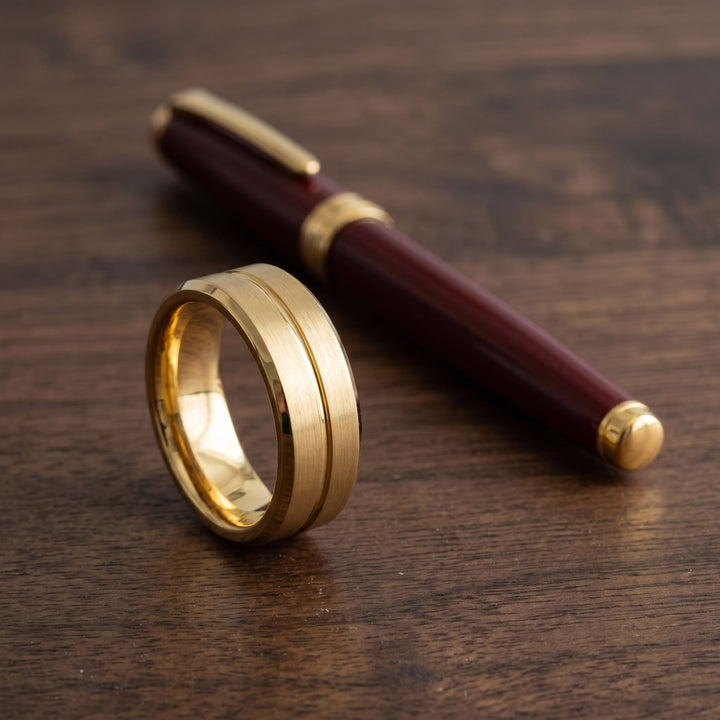 Gold Band on a walnut desk beside a burgundy fountain pen