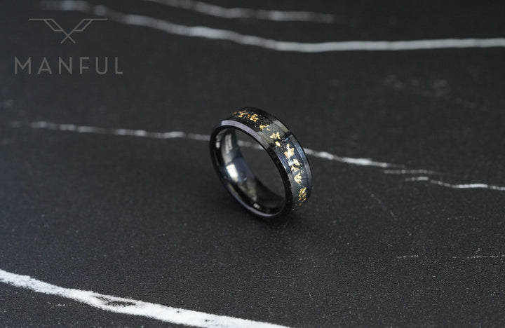 Gold Leaf Inlay Band Black, resting flat on a dark marble surface at an angle