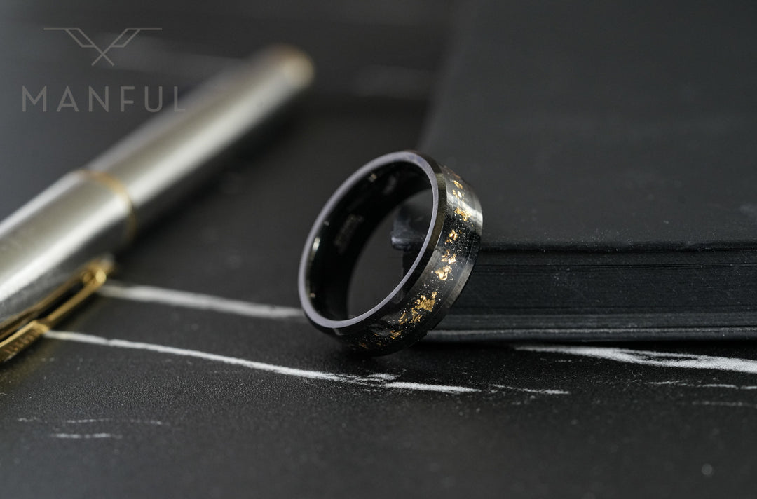 Gold Leaf Inlay Band Black, leaning against a black notebook beside a silver pen