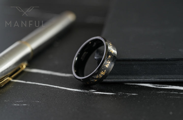 Gold Leaf Inlay Band Black, leaning against a black notebook beside a silver pen