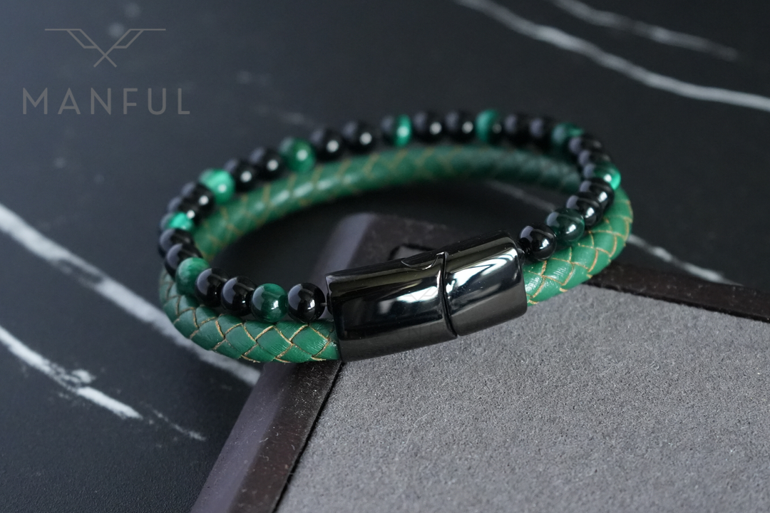 Jade Bead And Leather Bracelet, coiled on dark marble beside a brown leather strip prop