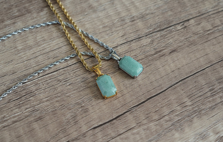 Jade Stone Pendant Gold, laid on wood beside a matching pendant on a silver chain