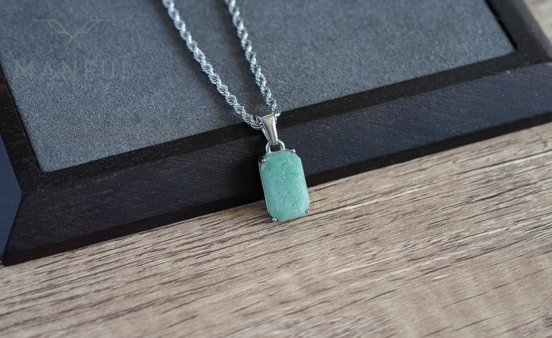 Jade Stone Pendant Silver, hanging straight on a wood surface with a dark leather corner behind it