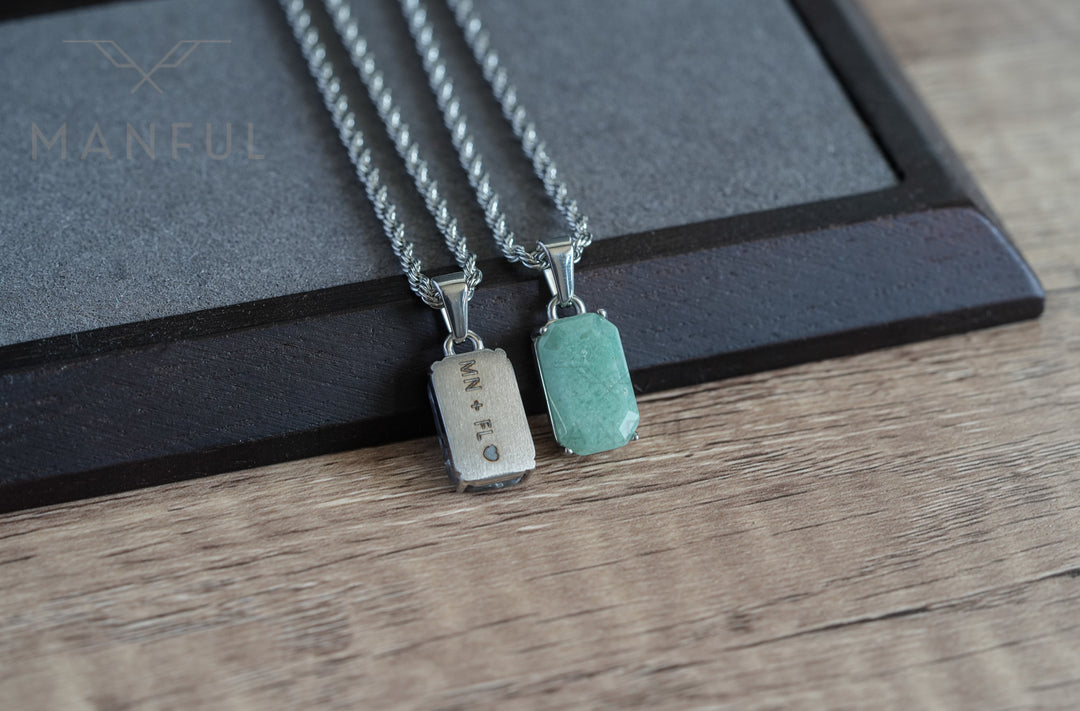 Jade Stone Pendant Silver, laid on wood beside a matching engraved silver tag pendant