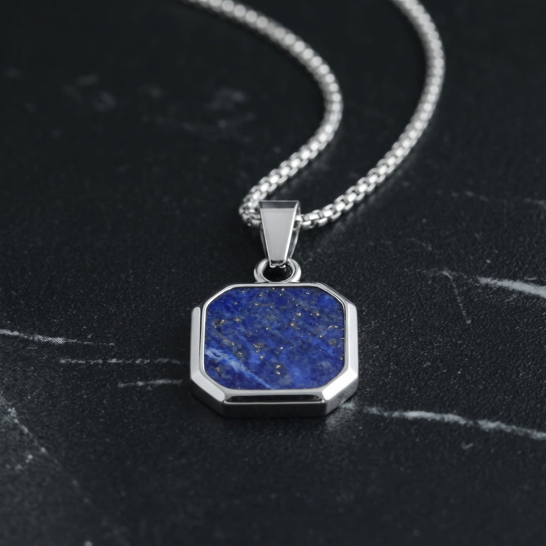 Lapis Square Necklace (Silver) lying on dark marble with the steel chain leading up