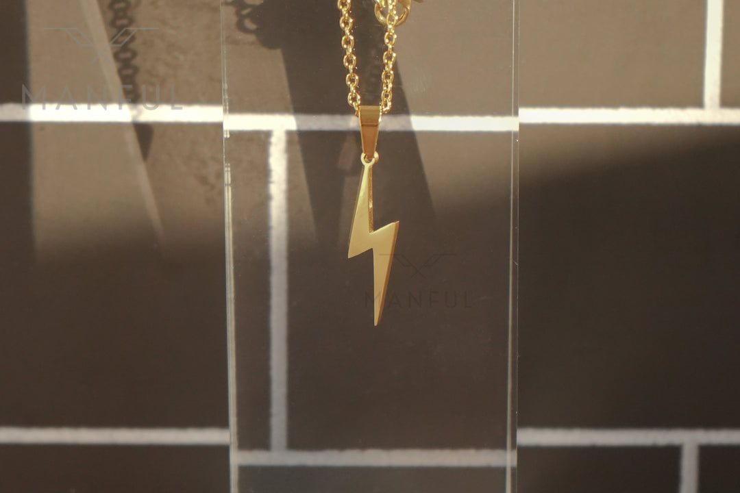 Lightning Pendant Necklace Gold, close up of the bolt against a warm tiled backdrop