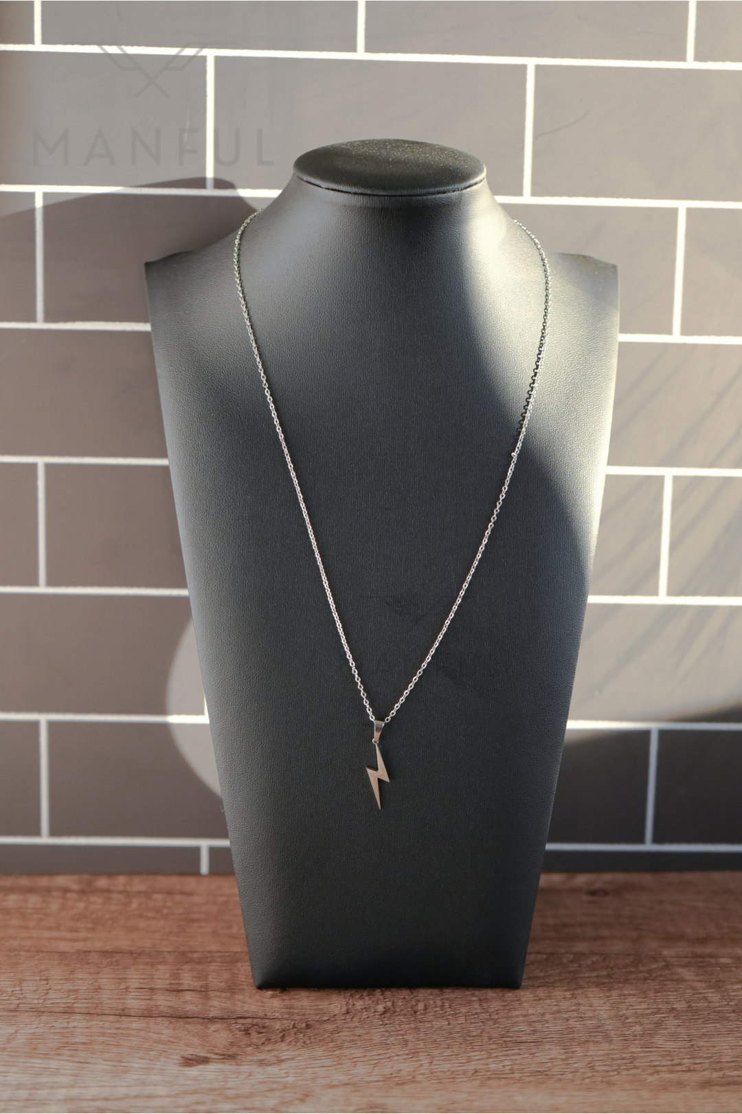 Lightning Pendant Necklace Silver, displayed on a black bust against a tiled wall