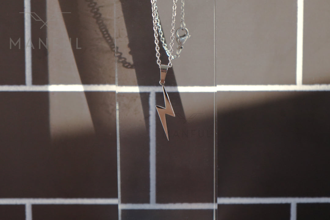 Lightning Pendant Necklace Silver, close-up of the bolt pendant against a tiled wall