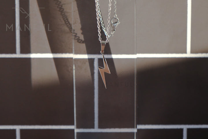 Lightning Pendant Necklace Silver, close-up of the bolt pendant against a tiled wall