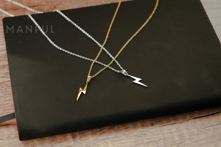 Lightning Pendant Necklace Silver, silver and gold colourways compared side by side on a book