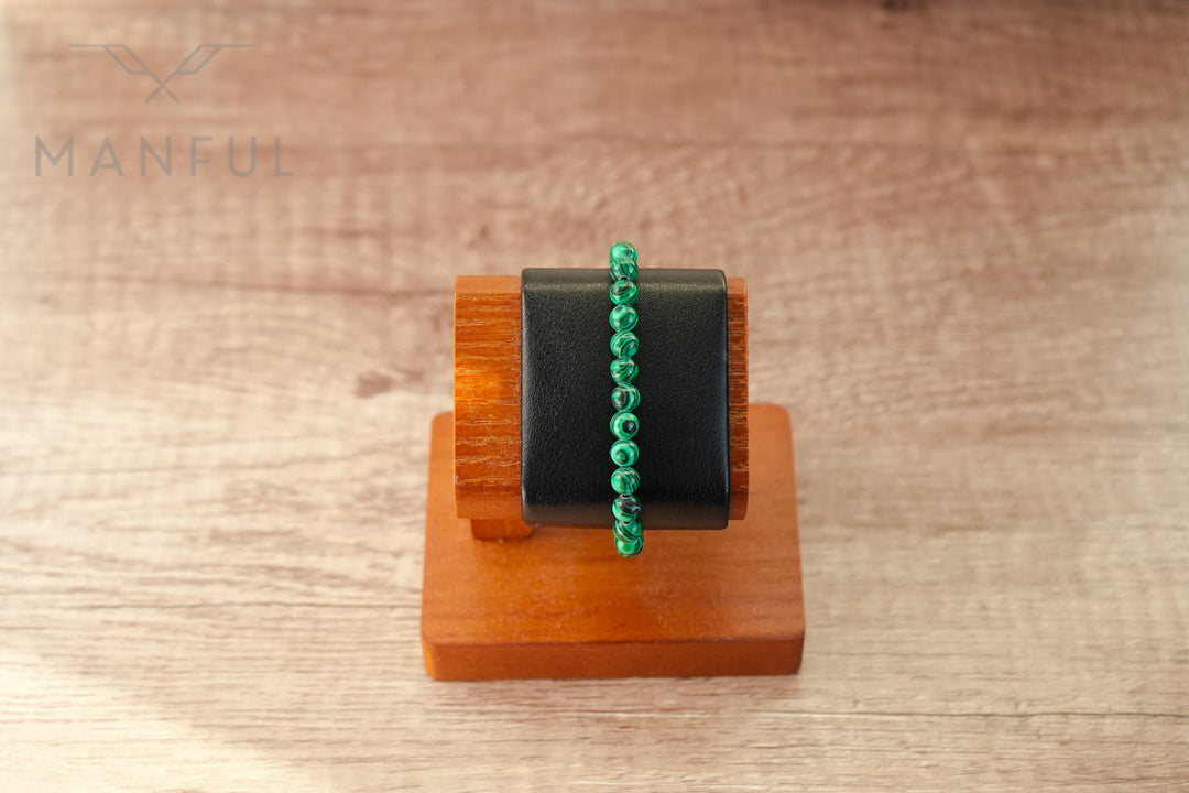 Malachite Bead Bracelet, displayed stretched across a small round bracelet stand