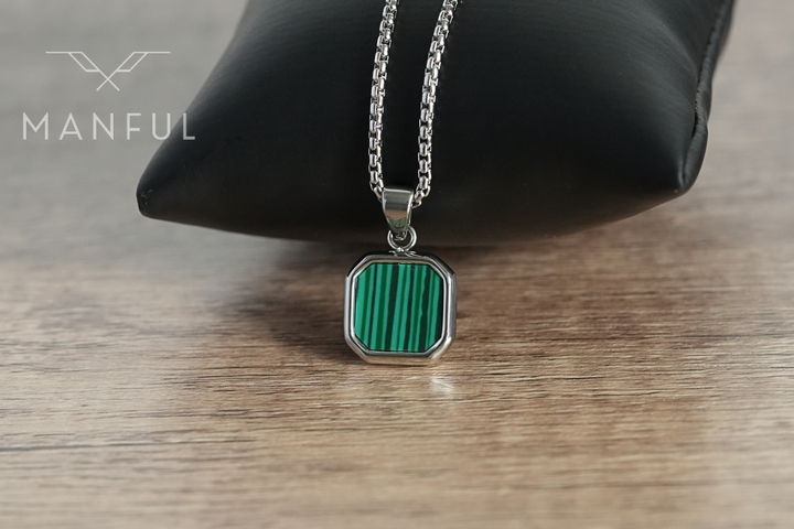 Malachite Square Necklace Silver, draped over a black display cushion on a wood surface