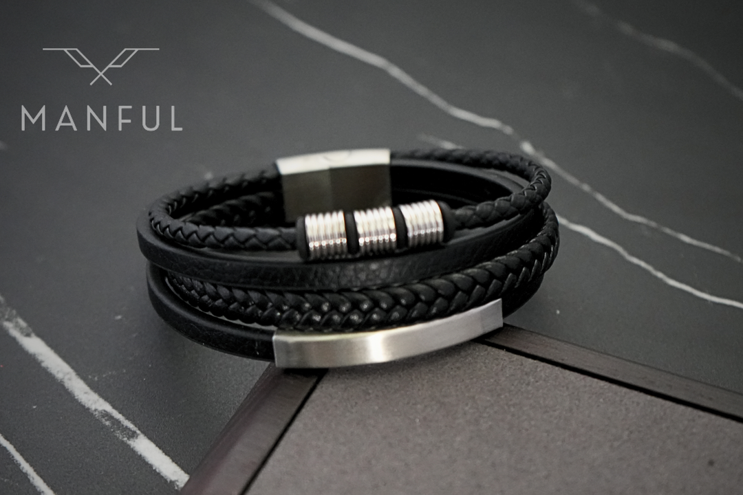 Black & Silver Leather Bracelet, coiled on a dark marble surface showing the silver clasp
