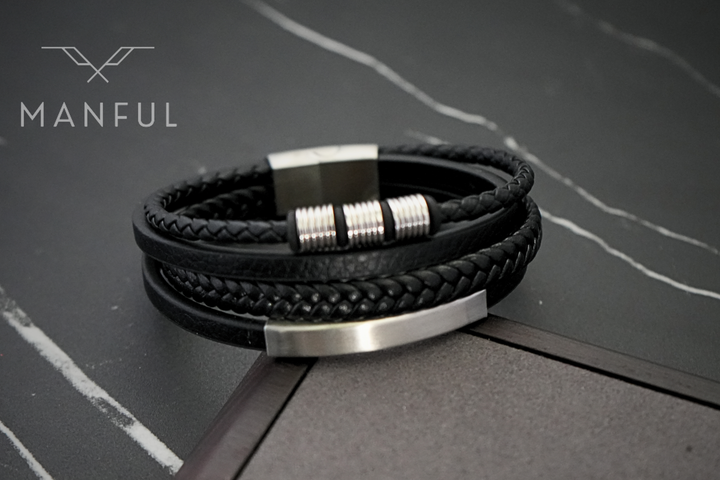 Black & Silver Leather Bracelet, coiled on a dark marble surface showing the silver clasp